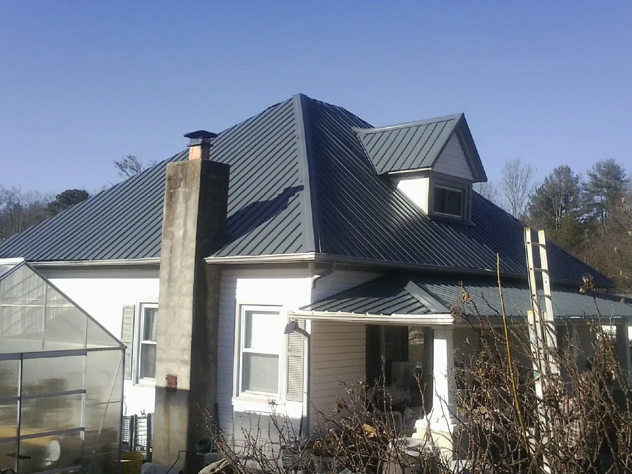 Dark blue standing seam metal roof on a white farmhouse with dormer — Slate & Tile Roof Repair by Roofing Brothers in Marysvale