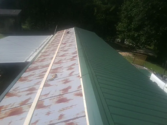 Old rusted panels beside newly installed green metal roofing — Wind Damage Roof Repair by Roofing Brothers in Marysvale