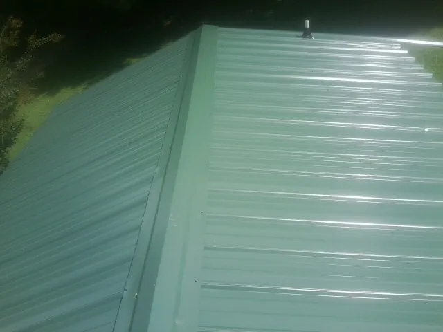 New green metal panels meeting at the ridge of a roof — Flat Roof Repair work by our crew in Marysvale