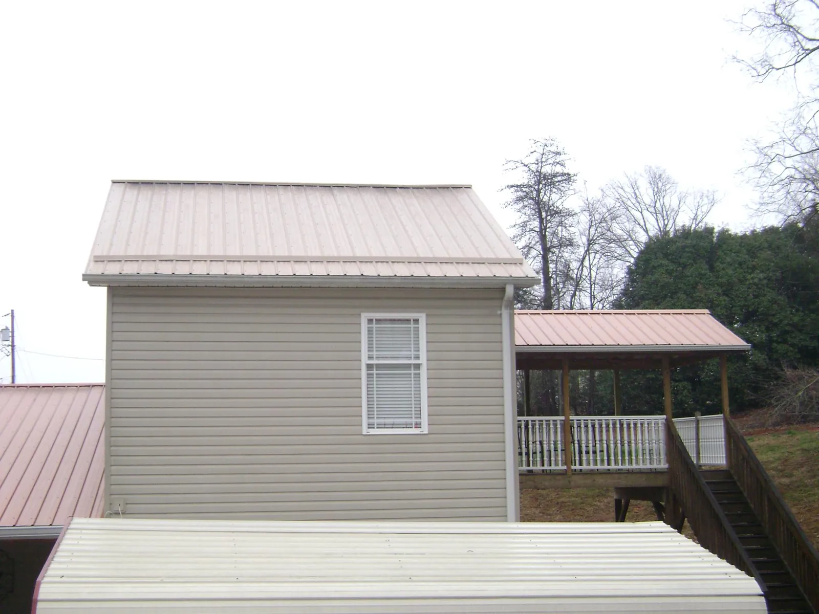 Tan metal roofs on a two story addition and attached porch, from a Roof Replacement job in Marysvale