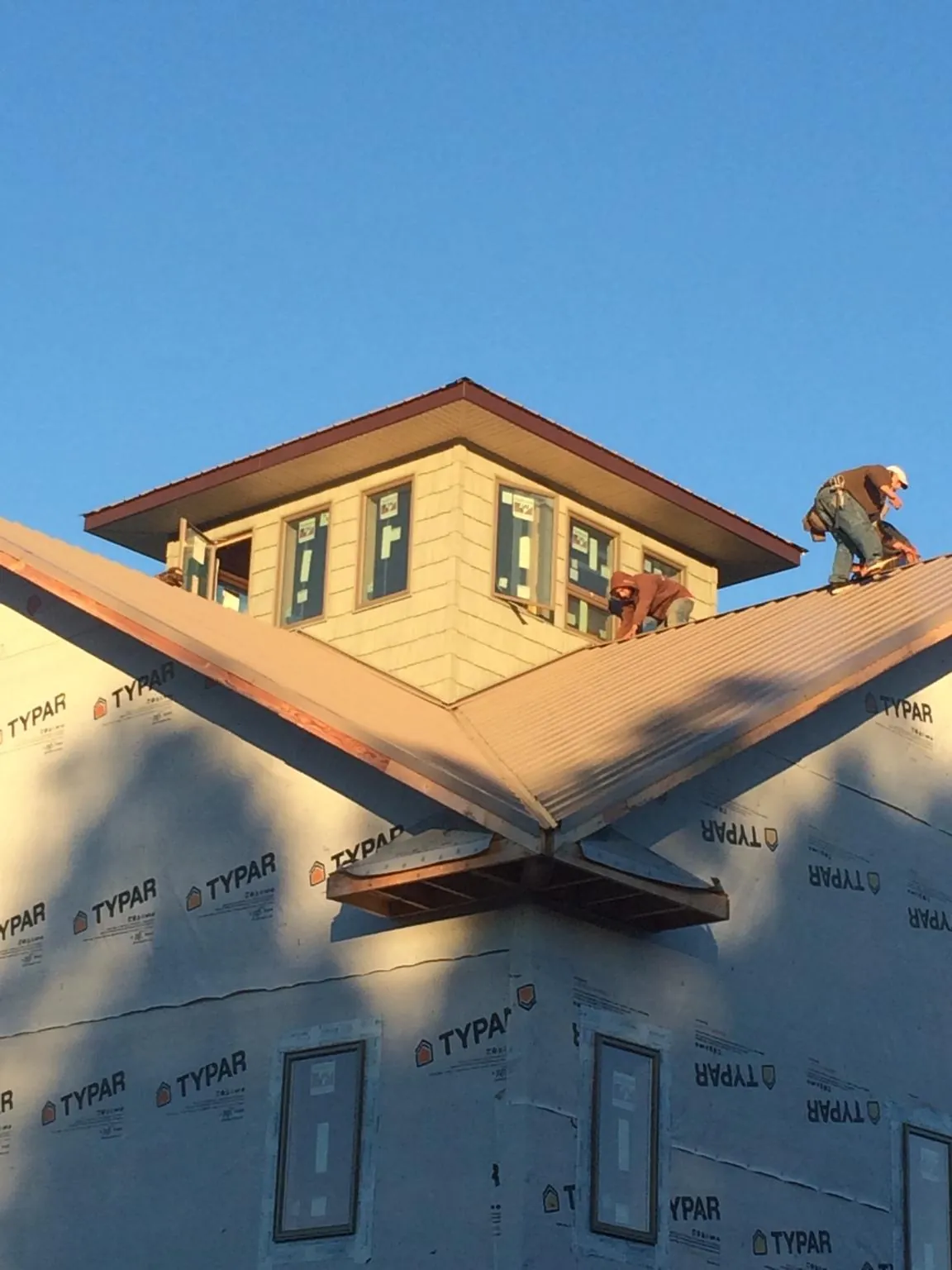 Roofers working around a rooftop cupola on a new metal roof at sunset — Roof Waterproofing in Marysvale by Roofing Brothers